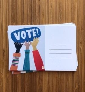 A stack of postcards with hands reaching towards the word VOTE