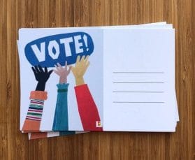 A stack of postcards with hands reaching towards the word VOTE