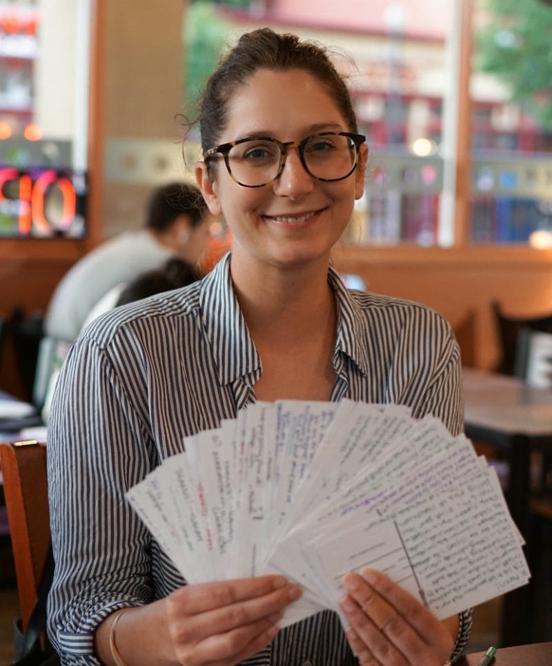 Female Washington DC volunteer holds a stack of postcard to voters as a fan at Sister District candidate event for Maria Collett