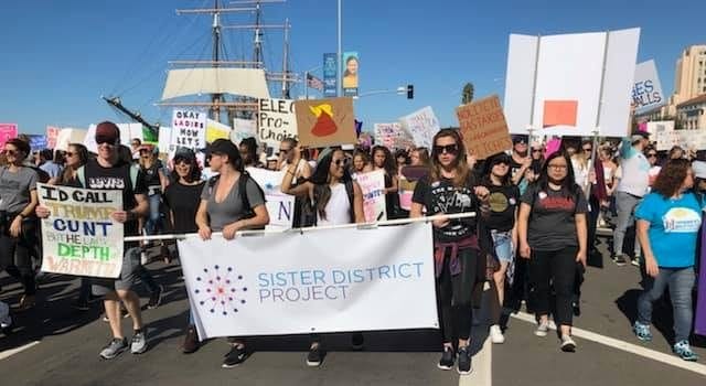 Volunteers march with Sister District Project sign in San Diego