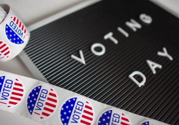 A board that reads Voting Day next to I voted stickers