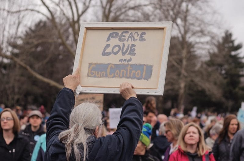 Protester holds sign reading "peace love gun control"