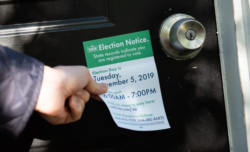 Hand placing Election Notice for November 5 on door