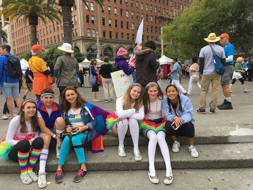 group of six Sister District volunteers dressed in rainbow clothing while rallying for equal rights