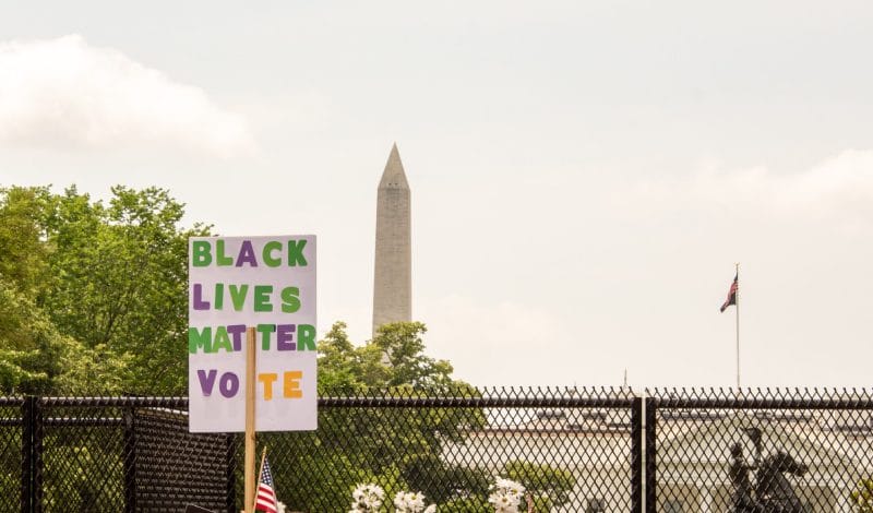 Protest sign reading black lives matter - vote in front of the Washington Monument and White House